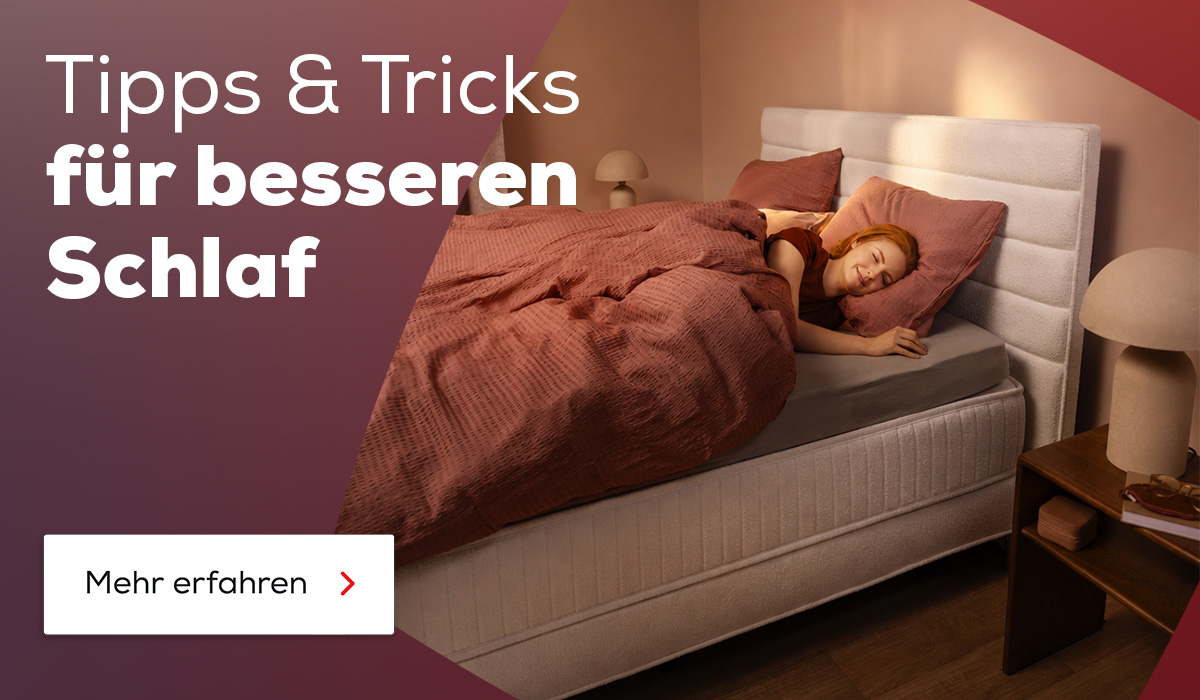Frau liegt glücklich im Bett und schläft. Entdecke jetzt Tipps und Tricks für besseren Schlaf.